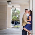Engagement session by Brisson Imagery. Couple kisses at a local Charleston Office building with exterior arches and lanterns