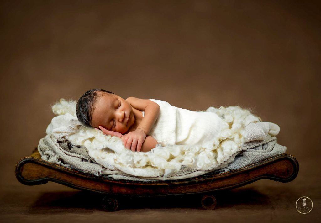 Newborn Baby boy laying on a bed of cream colored blankets sleeping. Portrait by Brisson Imagery