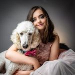 girl poses with a white poodle