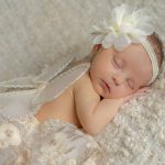 Newborn baby girl posed on her tummy wearing cream skirt on a cream backdrop with fairy wings. Portrait by Brisson Imagery