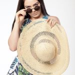 Teen girl poses in studio with sun hat and sunglasses