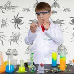 boy dressed as a scientist looks shocked as he looks into a Petry dish
