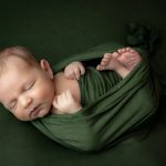 Newborn baby boy in green in the huck fin pose portrait by Brisson Imagery
