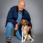 older man poses with his hound dog