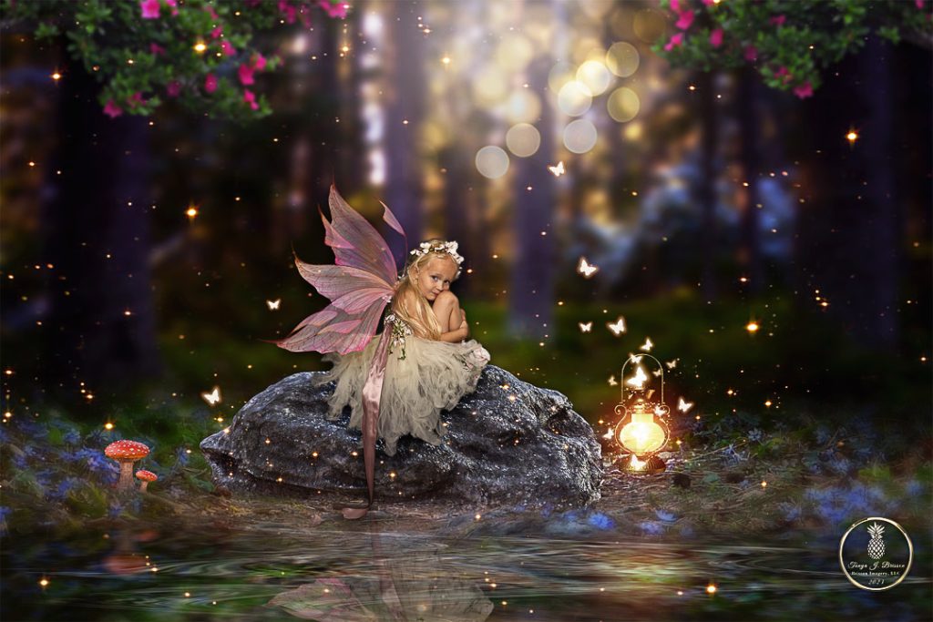 Little girl dressed as a fairy sits on a rock surrounded by fireflies. Image by Brisson Imagery,LLC